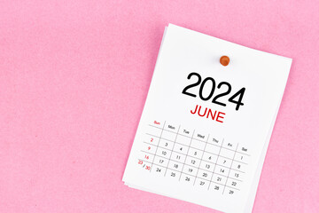 June 2024 calendar page and wooden push pin on pink background.