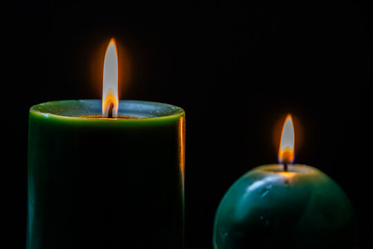 Two green candles grouped on dark surface.
