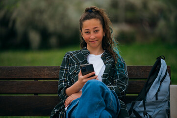 Beautiful young girl using smart phone in the park.
