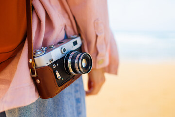 girl with a camera. female traveler with backpack and camera stands on the beach and enjoys the sea...