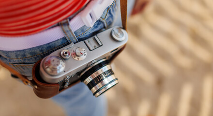 Close-up of a film camera. a young girl in stylish clothes takes photographs with a film camera....