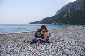 Woman and kid looking for rocks in pebble beach