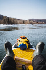 A man floats on a sapboard on the river, spring rafting on the lake, yellow dry bag, tourist...