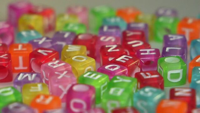 multicolored cubes, many Eenglish letters, slowly rotating on a white background.