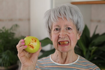 Senior woman with bloody gums after bitting an apple 