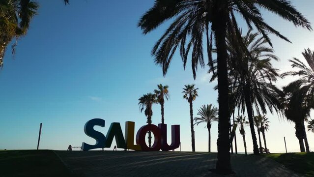 colorful letters of Salou town, palm trees andl beach at sunset, Catalonia, Spain 4k