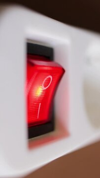 Turn on the electricity supply by pressing the red push button switch of the white power strip. Vertical video.
