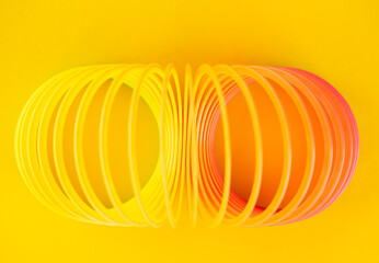 Toy plastic rainbow spiral on a yellow background. Top view, selective focus.