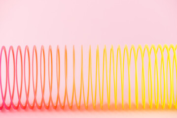 Stretched plastic rainbow toy on a pink background. 90s toy, nostalgia, retro.
