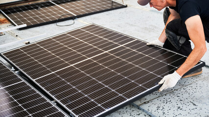 Worker building solar panel system on metal rooftop of house. Man engineer in gloves installing...