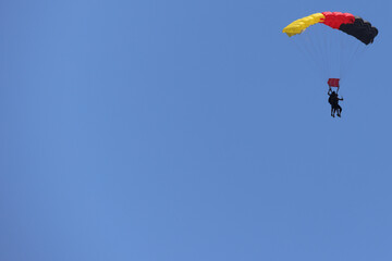 Tandem skydiving (parachuting), clear blue sky day. Parachute decorated in the Germany flag colors. Copy space.