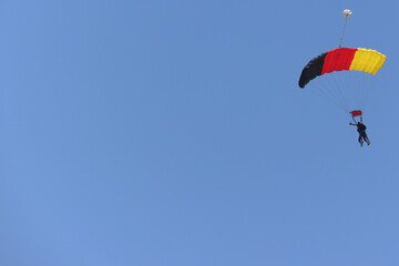Tandem skydiving (parachuting), clear blue sky day. Parachute decorated in the Germany flag colors....
