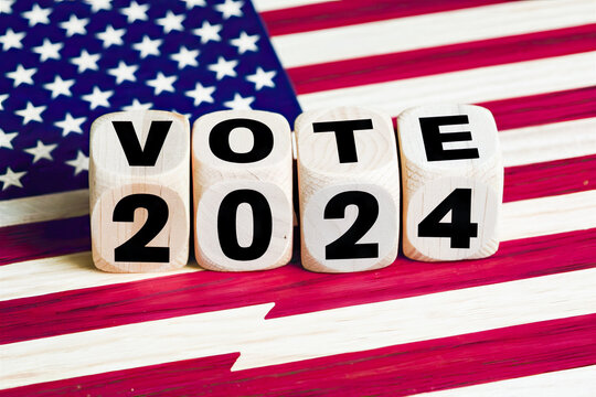 Wooden cubes with text VOTE 2024, lying on the USA flag as backdrop.United States presidential election in 2024