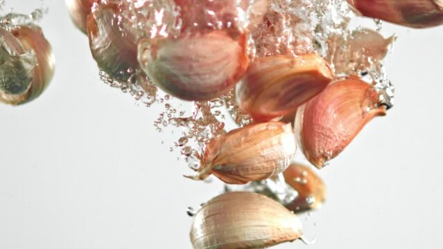 Super slow motion fresh garlic falls into the water with splashes. High quality FullHD footage