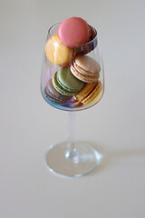 Champagne glass full of colorful macaroons on the table. Selective focus.