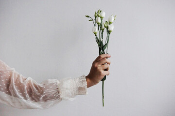 gentle bouquet of white flowers in the hand. flatlay composition with copyspace. female hand holds...