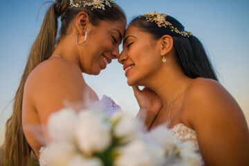 mujeres jovenes al aire libre mirandose frente a frente mientras sonrien y usan sus vestidos de bodas 