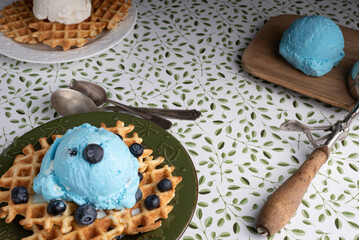 Indulgence for breakfast or a snack.  Ice cream and waffles with fresh, healthy blueberries with a green and white background.