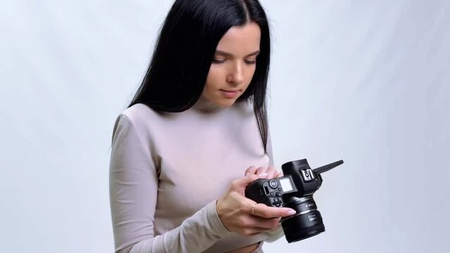 Young beautiful photographer with the professional camera looks at the photos on the camera