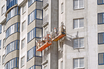 Window sill installation, new building construction. Workers using lift platforms to install window sills on new construction site, enhancing the building's facade. Suspended platform work