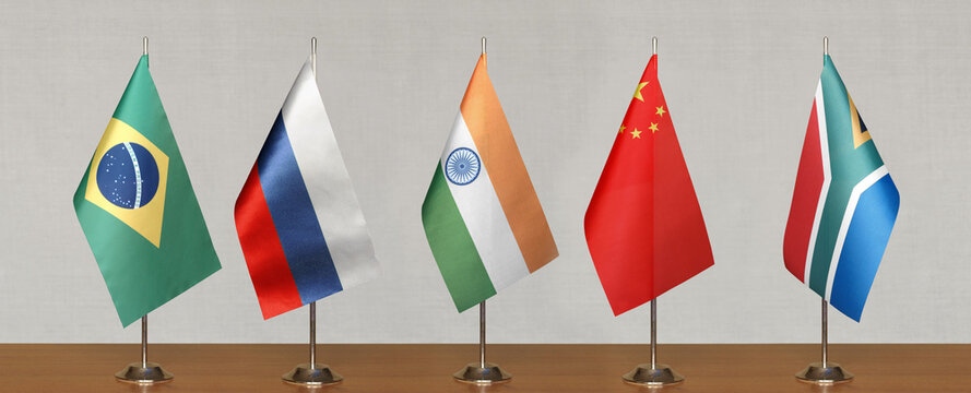 Tabletop flags of BRICS countries on a gray blurred background