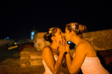 mujeres jovenes latinas sonriendo y mirandose frente a frente en la noche en la ciudad 