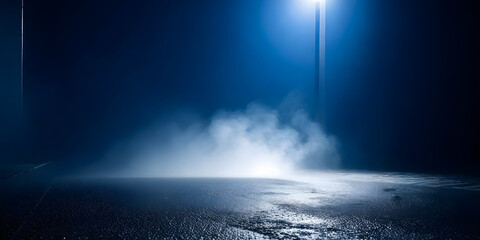 A street light shines brightly in the middle of a dark, empty street, casting a cone of light on...