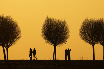 black silhouettes against the colourful background of the setting sun with with some people