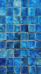 A grid of cracked, weathered ceramic tiles in a range of vibrant blue hues, forming an abstract and textural background with a vintage aesthetic.