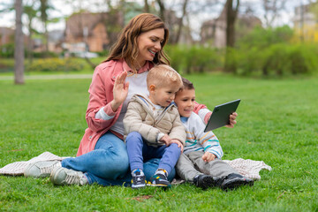 Naklejka na ściany i meble Mother and kids using tablet to talk online