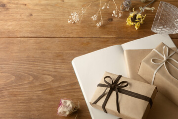 Nostalgic photos of wooden tables with dried flowers such as rose and sunflower, gift boxes with natural taste, notebooks, books, and clear glasses	