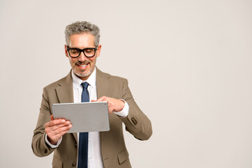 Seasoned businessman with grey hair and glasses confidently using a tablet, his smile suggesting ease with technology that bridges the gap between traditional business acumen and modern digital trends