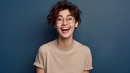 Joyful young adult in casual beige tee, clear eyeglasses, and messy hair. Expressive happiness, studio portrait. Optimistic mood, trendy style. AI - obrazy, fototapety, plakaty