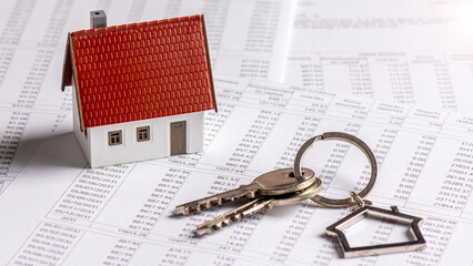 Trousseau de clés et maquette de maison individuelle posés sur un document bancaire d'échéancier de prêt immobilier. Concept d'achat immobilier à crédit, de durée et de taux d'intérêt d'emprunt