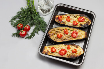 Fototapeta na wymiar Grilled baked eggplant with tomatoes in pallet. Dill and tomatoes on table