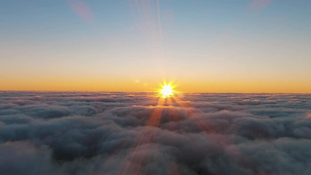 Witness the stunning sunrise over the clouds, painting the sky in a warm afterglow. The suns rays create a serene atmosphere in the natural landscape