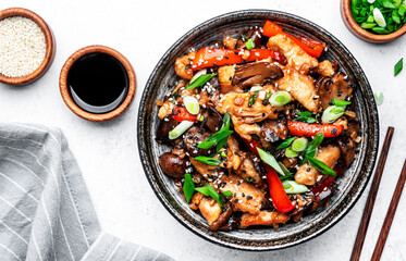Hot stir fry chicken  slices with red paprika, mushrooms, chives and sesame seeds with ginger, garlic and soy sauce. White table background, top view