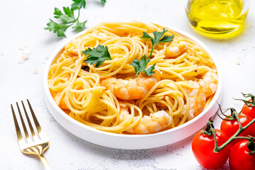 Delicious spaghetti pasta with big shrimp on plate with parsley, white table background. Top view - 779782073