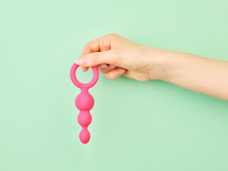 Woman's hand holding adult sex toy over mint background - obrazy, fototapety, plakaty