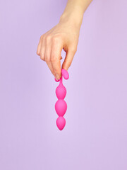 Woman's hand holding adult sex toy over violet background - 779789641