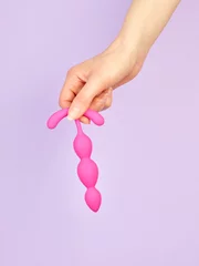 Tuinposter Woman's hand holding adult sex toy over violet background © Nik_Merkulov