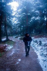 Latino hiker exploring snow-covered Guadarrama forest at twilight, promoting rural tourism.