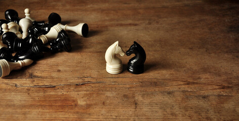 Antique chess pieces, black and white knight on shabby wooden table. The remaining chess pieces...