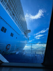 A large cruise ship is seen from the deck of a smaller ship