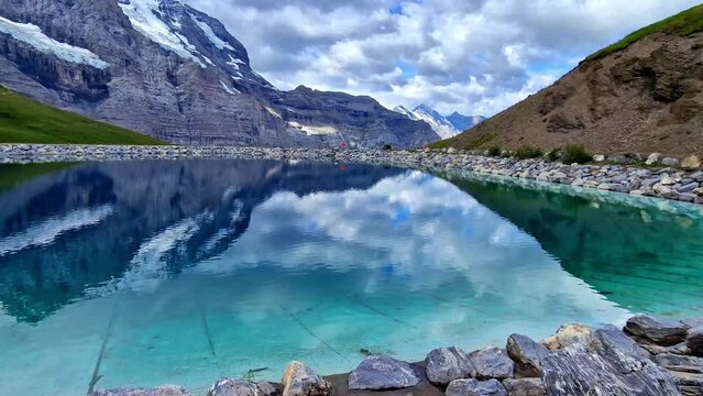 amazing Swiss nature . panoramic view of Fallboden lake with turquoise water and reflections of snowy peaks. Kleine Scheidegg mountain pass famous for hiking in Bernese Alps.
