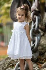 Cute little girl in white dress, posing and smiling - 779805621