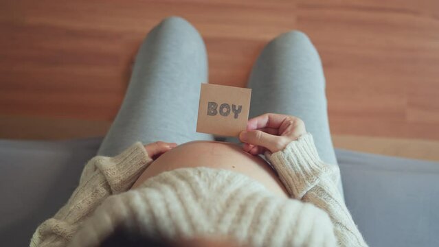Pregnant female showing paper with boy word. pregnant woman waiting for a boy.