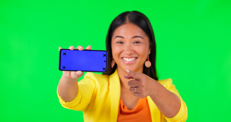 Woman face, green screen and hand pointing to phone mockup with tracking markers on studio background. Portrait, space and asian lady person showing product placement for news or how to steps for app