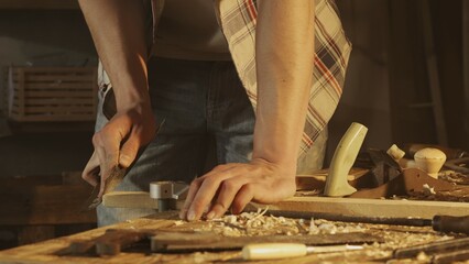 Male woodworker working in garage. Man professional carpenter working with wooden materials in workshop and sanding wooden panel with sandpaper.