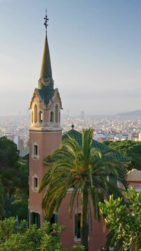 Green palms and flora in Park Guell. City of Barcelona, Spain is seen in the background. Vertical Screen